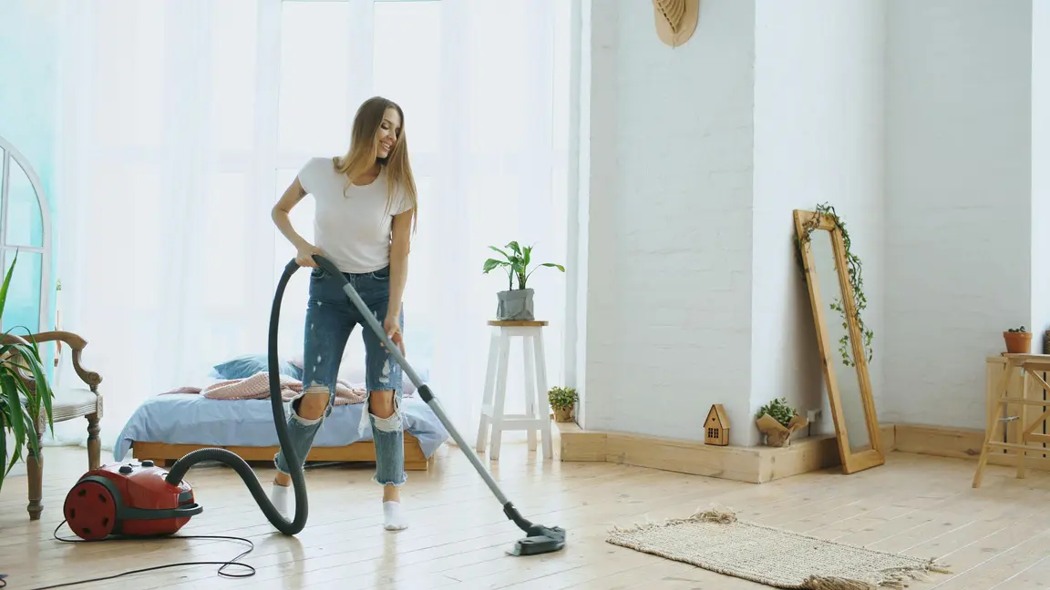 A professional cleaner vacuuming a bright living room